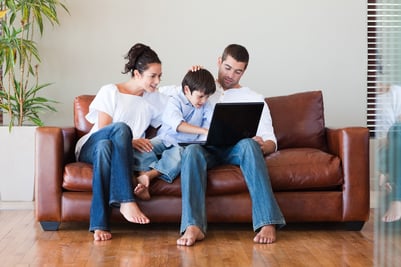 Parents and son playing together with a laptop on a couch