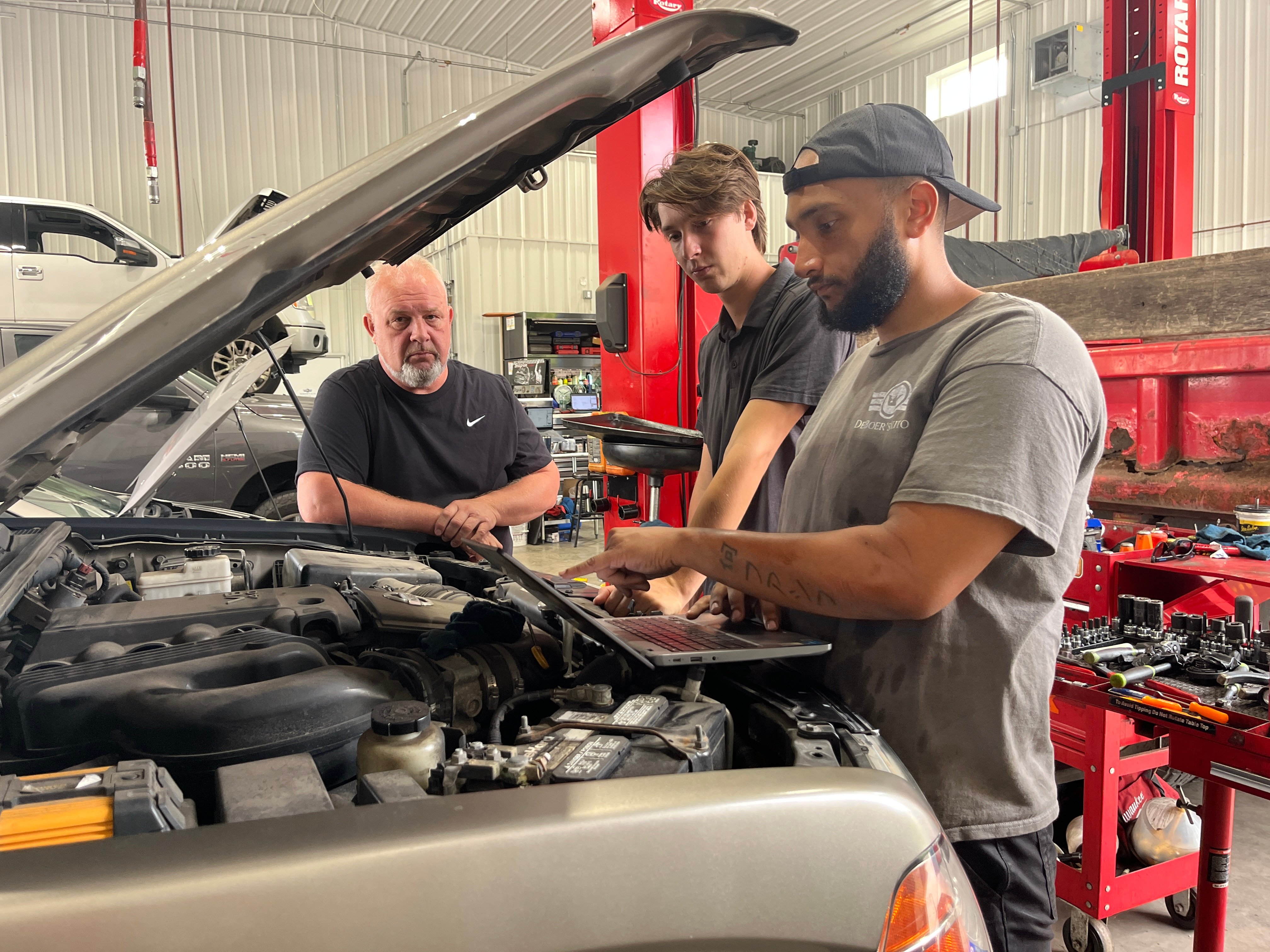 DeBoer's Technician and advisor review under the car hood with customer